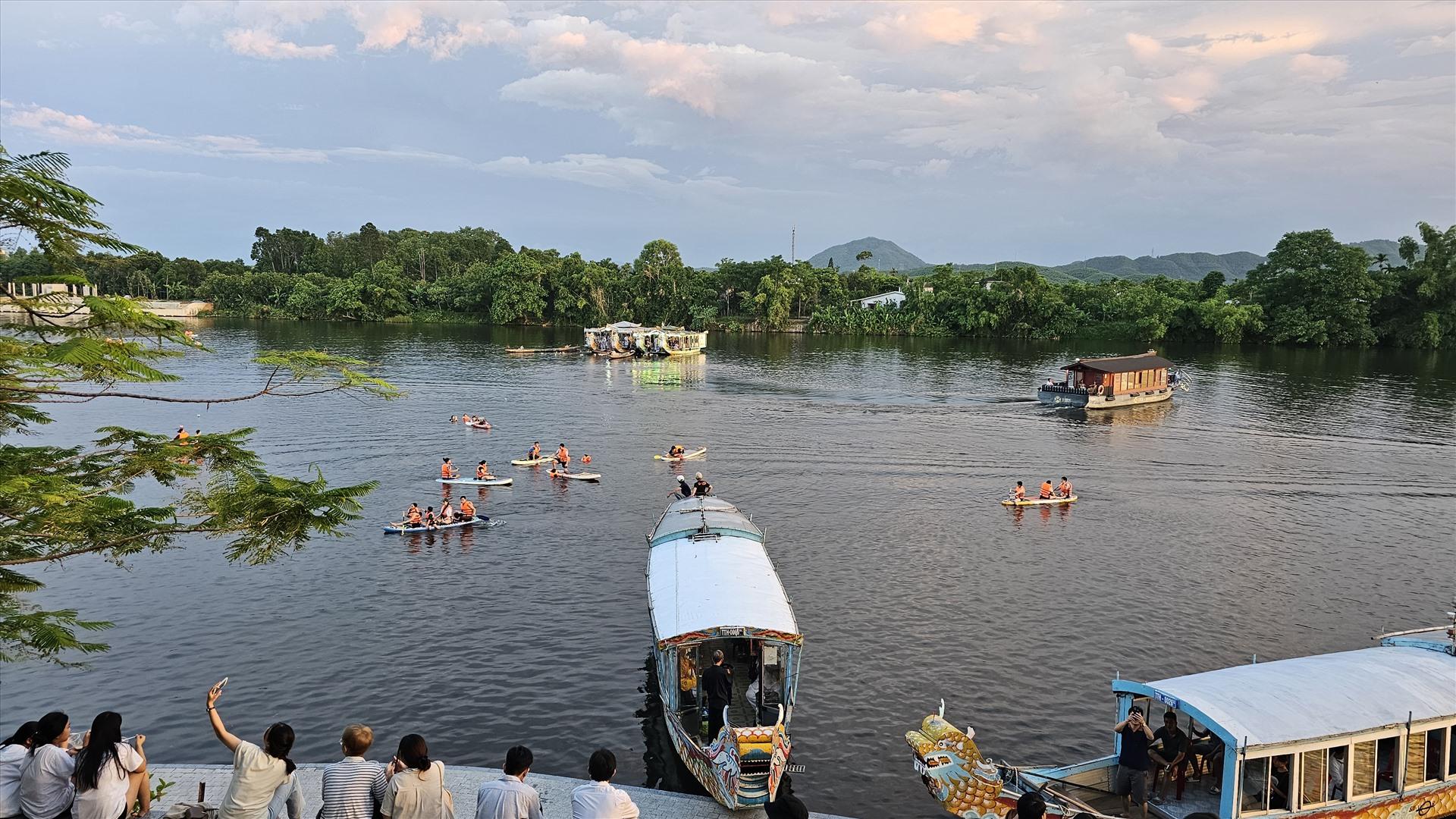 Hoạt động chèo SUP tại một góc khu vực trước chùa Thiên Mụ, bên cạnh đó là những chiếc thuyền rồng chở du khách đang neo đậu ngắm hoàng hôn.