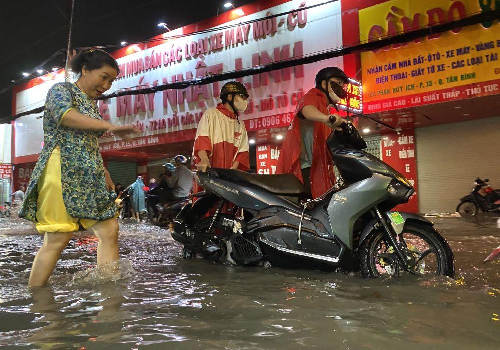 Người dân vất vả trên đường về nhà. Chị Nguyễn Thị Oanh (quận Gò Vấp) cho biết đường Phan Huy Ích thường xuyên ngập nặng mỗi khi mưa lớn.