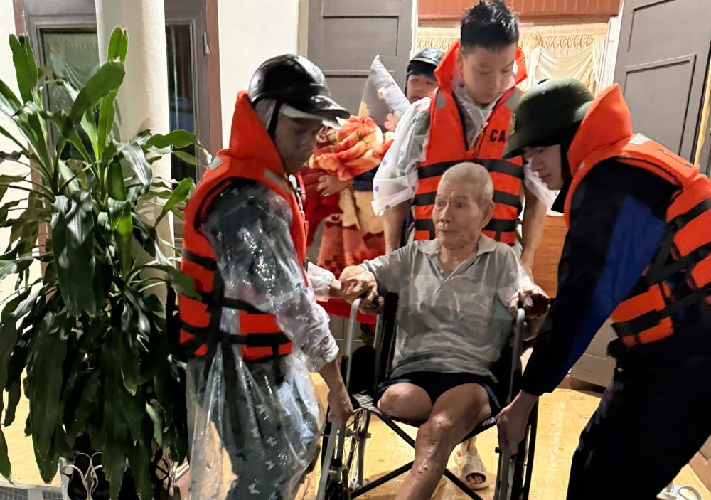 Hỗ trợ sơ tán người già đến nơi cao để tránh ngập lụt. Ảnh: Hàn Nguyên