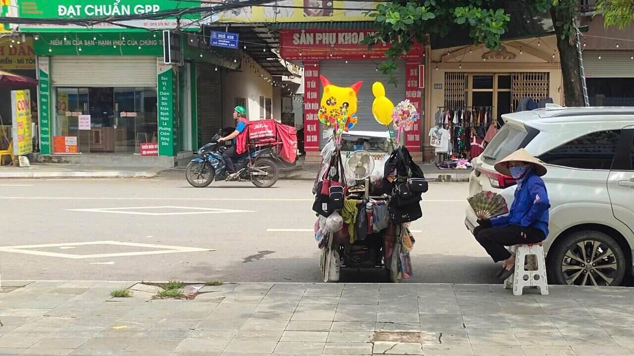 Giữa cái nắng gay gắt, chị Hường (45 tuổi, quê ở Ân Thi, Hưng Yên) vẫn miệt mài đẩy chiếc xe hàng rong quen thuộc trên phố. Ảnh: Bình Khang.