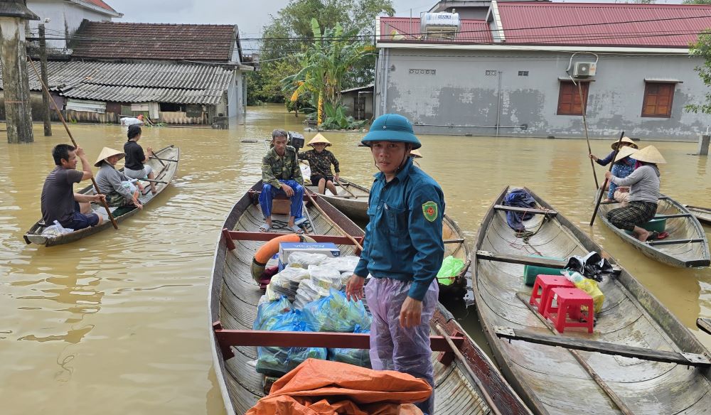 Cơm được đưa vào nhà tránh lũ, người dân chèo đò đến nhận cơm với niềm vui. Ảnh: Hưng Thơ