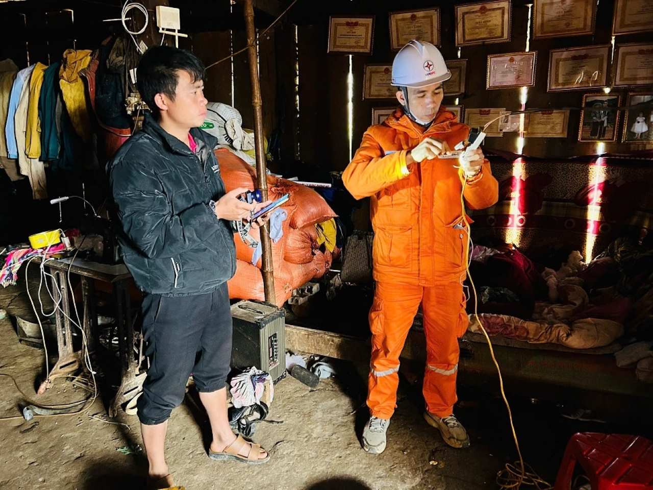 Nhân viên Đội Quản lý Điện giúp dân lắp thiết bị điện. Ảnh: Thu Hiền