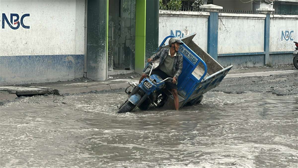 Một phương tiện di chuyển qua hố sâu bị nghiêng xe. Ảnh: Minh Tâm