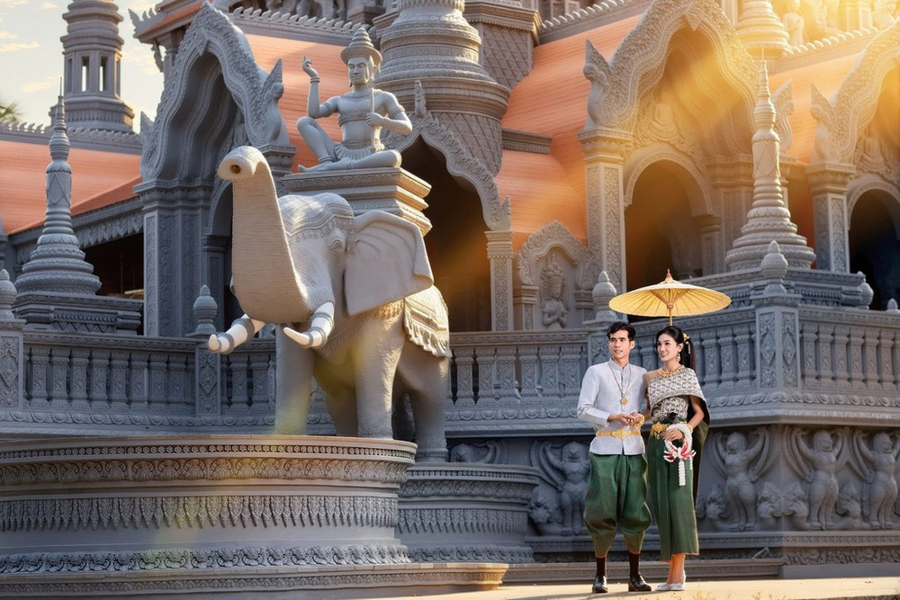 Trong ngày vui trọng đại, chú rể thường khoác lên mình chiếc áo cổ đứng uy nghi, rực rỡ và quấn K’bên (một mảnh vải dài được quấn quanh eo, luồn qua hai chân và giắt lên thắt lưng tạo thành hình dáng như chiếc quần thụng ngắn). Cô dâu lại càng kiêu sa hơn với áo ngắn tay hoặc dài tay ôm sát, kết hợp cùng váy Som-pốt Hôl hoặc cũng quấn K’bên. (Ảnh: Chú Râu)