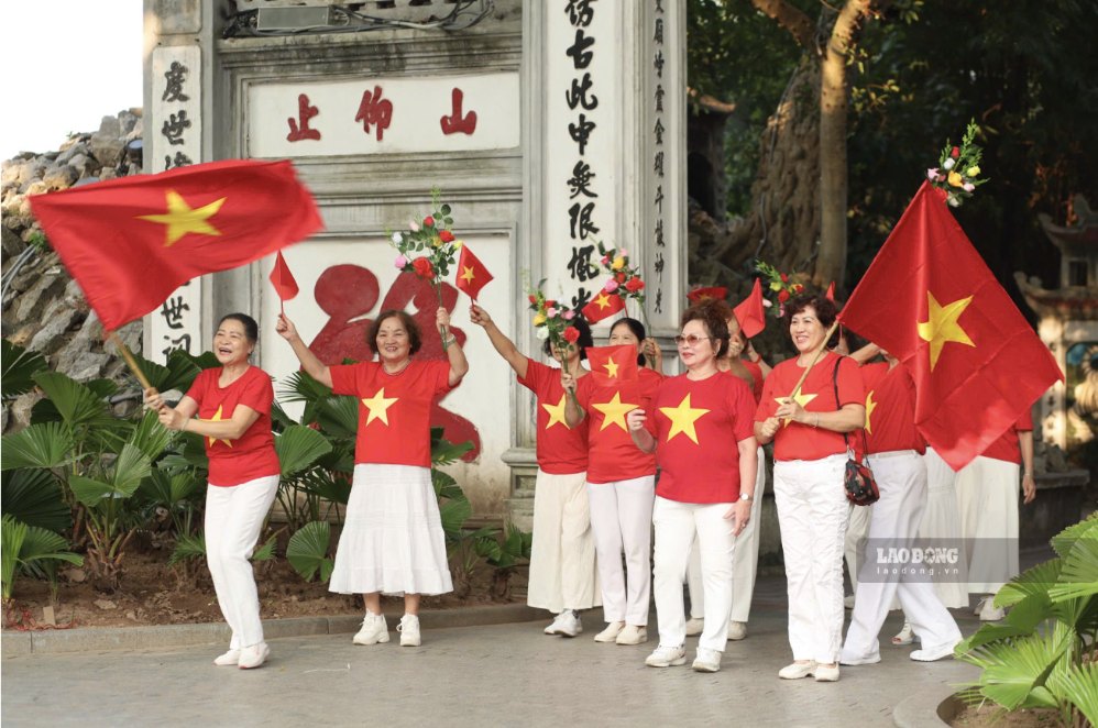 Người dân chụp ảnh lưu niệm bên các biểu trưng chào mừng Ngày Giải phóng Thủ đô. Ảnh: Kim Thủy